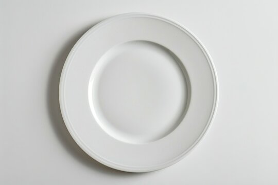 A simple white plate on a clean white table. Suitable for various food and kitchen concepts
