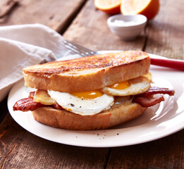 Egg sandwich with bacon on white plate
