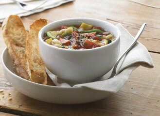 Bowl of vegetable soup with bread and spoon