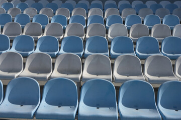 Blue and grey empty plastic seats on the stands of a sports stadium