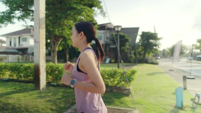 A beautiful Asian woman is jogging in a park in the amber-orange evening sun, A woman with long dark hair jigs and wants to stay in shape, Exercise to stay healthy.