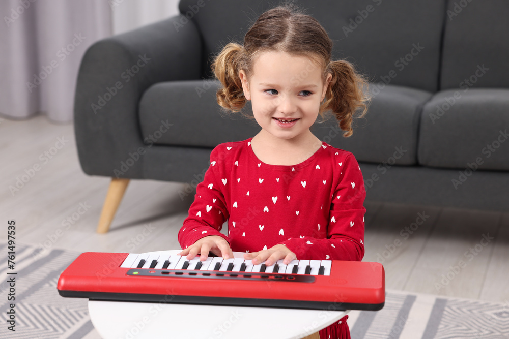 Wall mural Little girl playing toy piano at home