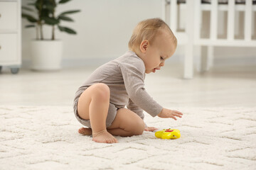 Children toys. Cute little boy playing with colorful toy on rug at home