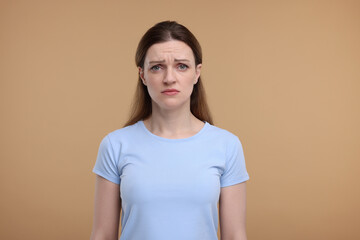 Portrait of sad woman on beige background