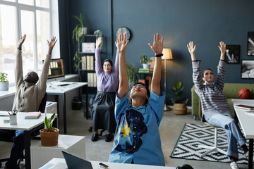 Multiethnic group of people enjoying stretching and breathing exercises while working in office...