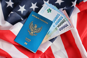 Naklejka premium Blue Republic Indonesia passport and money on United States national flag background close up. Tourism and diplomacy concept
