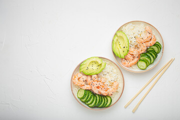 Two white ceramic bowls with rice, shrimps, avocado, vegetables and sesame seeds and wooden sticks on white concrete stone background top view. Healthy asian style poke bowl, space for text. - 761501715