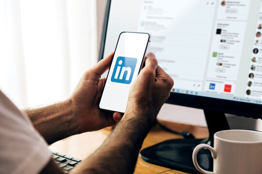 LinkedIn app on smartphone screen. Man holding a phone with a professional and business oriented social network service application. ROSARIO, ARGENTINA - MARCH 18, 2024.