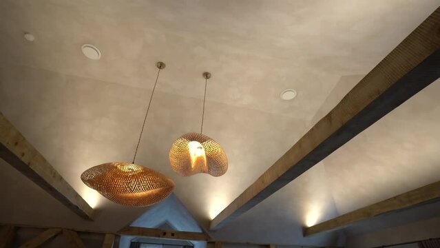 two woven pendant lights hanging from a textured ceiling with exposed wooden beams.
