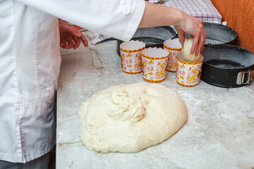 The confectioner girl prepares the dough for baking Easter cakes and stacked them into special forms