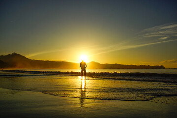 a man fishing on the beach at sunrise 