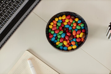Minimal top view background image of white table or desk in office with focus on bowl of colorful candy