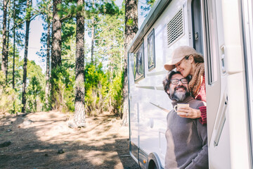 Happy people on travel lifestyle sitting on the door of a camper van parking in the nature forest...