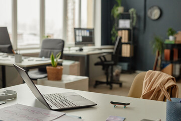 Background image of open laptop on workplace desk with clutter in empty office interior copy space