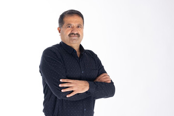 Happy mature man with arms crossed and looking at camera while standing against white background