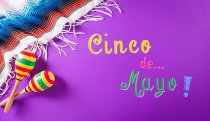 Cinco de Mayo holiday background made from maracas, mexican blanket stripes or poncho serape on purple background.