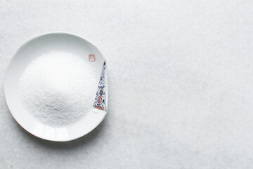 Overhead view of white sugar in a white plate, top view of granulated sugar in a plate