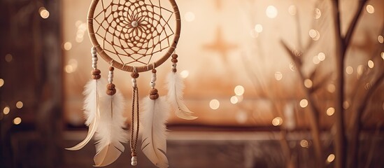 A fashion accessory dream catcher made of wood, metal and transparent material is hanging from a tree in a room, creating a beautiful decoration