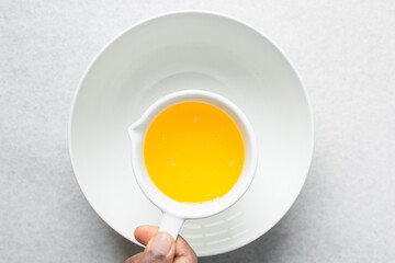 Pouring melted butter into a white mixing bowl
