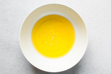 overhead view of melted butter in a white ceramic mixing bowl, top view of melted butter in white mixing bowl