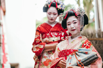 A pair of geishas in exquisite kimonos pause thoughtfully, their expressions a blend of tradition and the fleeting nature of the moment. They epitomize the timeless allure of Japanese culture
