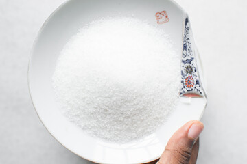 Overhead view of white sugar in a white plate, top view of granulated sugar in a plate