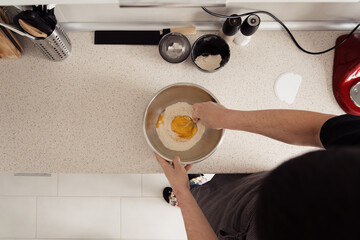 Overhead shot of hands mixing egg into flour for pasta.