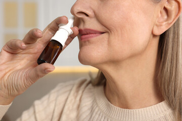 Medical drops. Woman using nasal spray indoors, closeup