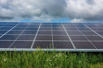 Photovoltaikanlage zur Stromerzeugung auf einem Acker vor wolkigem Himmel