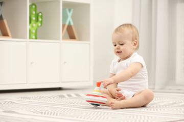 Children toys. Cute little boy playing with spinning top on rug at home, space for text