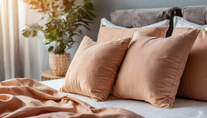 Soft pillows on top of bed, peach pink-colored. Minimalistic and cozy bedroom.