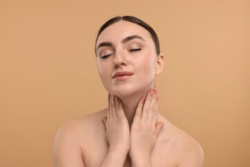 Beautiful woman touching her neck on beige background