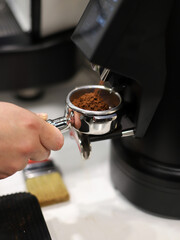 barista making coffee on handle of industrial coffee maker