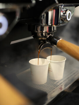 vasos llen&aacute;ndose de caf&eacute; en la cafetera del bar