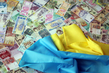 Ukrainian flag on many banknotes of different currency. Background of war funding and military...