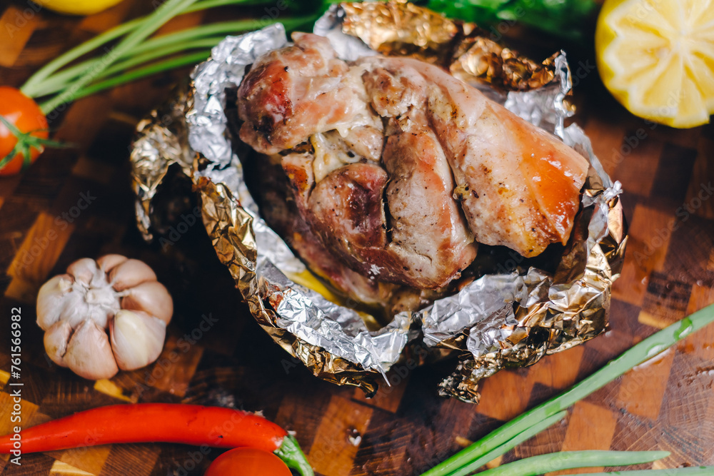 Wall mural roast pork in a smokehouse, standing on a cutting board, garnished with rosemary, pepper, chili pepp