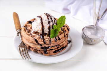 Stack of chocolate belgian waffles with ice cream and chocolate topping. Breakfast waffles with gelato, chocolate sauce drizzles and mint