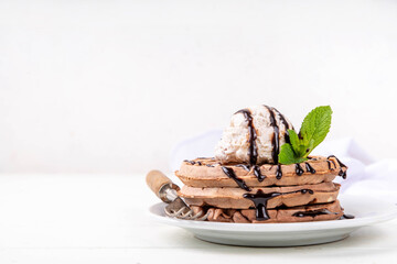 Stack of chocolate belgian waffles with ice cream and chocolate topping. Breakfast waffles with gelato, chocolate sauce drizzles and mint