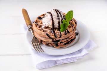 Stack of chocolate belgian waffles with ice cream and chocolate topping. Breakfast waffles with gelato, chocolate sauce drizzles and mint