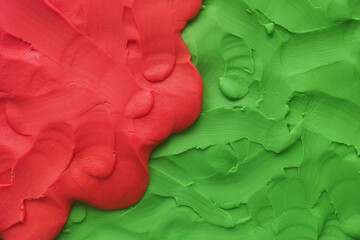A background texture made out of red and green play clay. Close up.