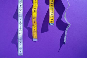 Multi-colored measuring tapes on a light background. Tool for measuring length and volume. Tape for...