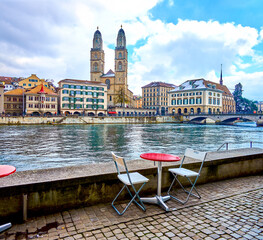 Restaurant's outdoor seating on the Wuhre riverside street with view on Grossmunster church, Zurich, Switzerland