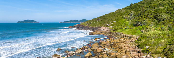 Coastline with beach, mountains and blue ocean with waves in Brazil. Aerial view of Saquinho beach. Florianopolis Santa Catarina..