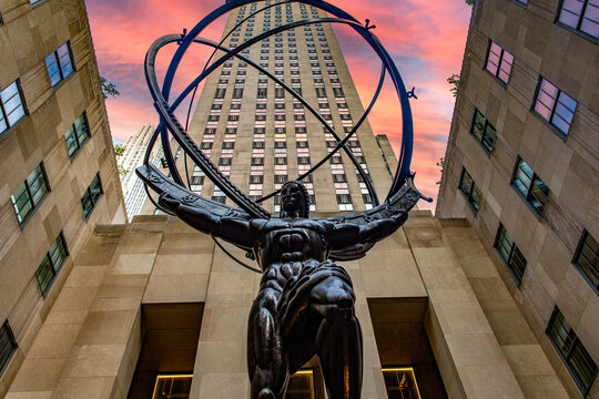 New York, USA; June 4, 2023: Atlas is a bronze statue with Rockefeller Center in the background at sunset or sunrise, inside the courtyard of the International Building, in Midtown Manhattan.