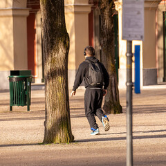 A man jogs in a park while listening to music in his headphones.