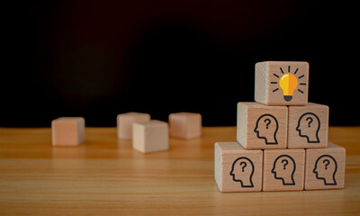 Team creative idea or innovative idea concept, Brainstorming process, Wooden blocks with question mark head icon stacked in pyramid stair shape and the top one with light bulb.