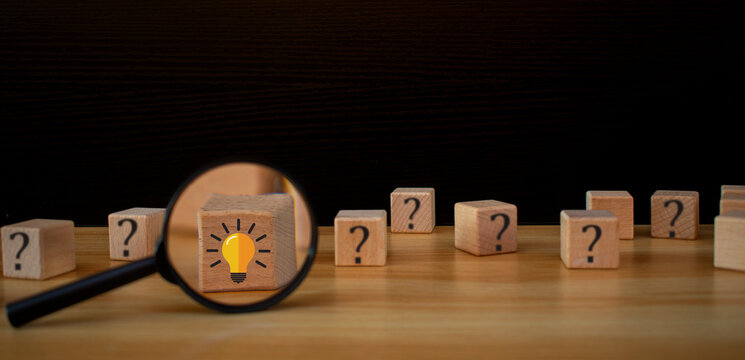 Team creative idea or innovative idea concept and search concep. Brainstorming process, Wooden blocks with question mark head icon stacked in and the light bulb in magnifying glass on wood table.  - Powered by Adobe