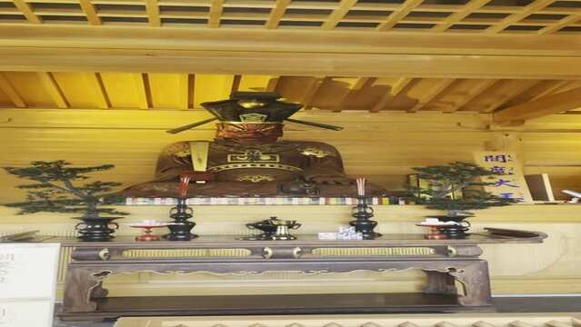 Red Kami sama statue with golden features in Todoroki - Tokyo - Japan. Kuhonbutsu Joshinji Temple. camera sliding up motion from donation wood box to the statue - vertical FullHD footage. 