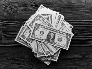 Heap of one dollar bills over black wooden planks background