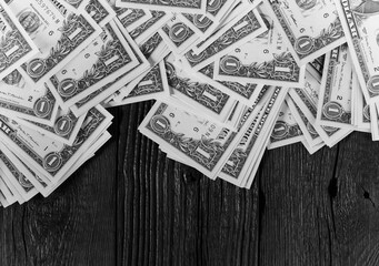 Heap of one dollar bills over black wooden planks background